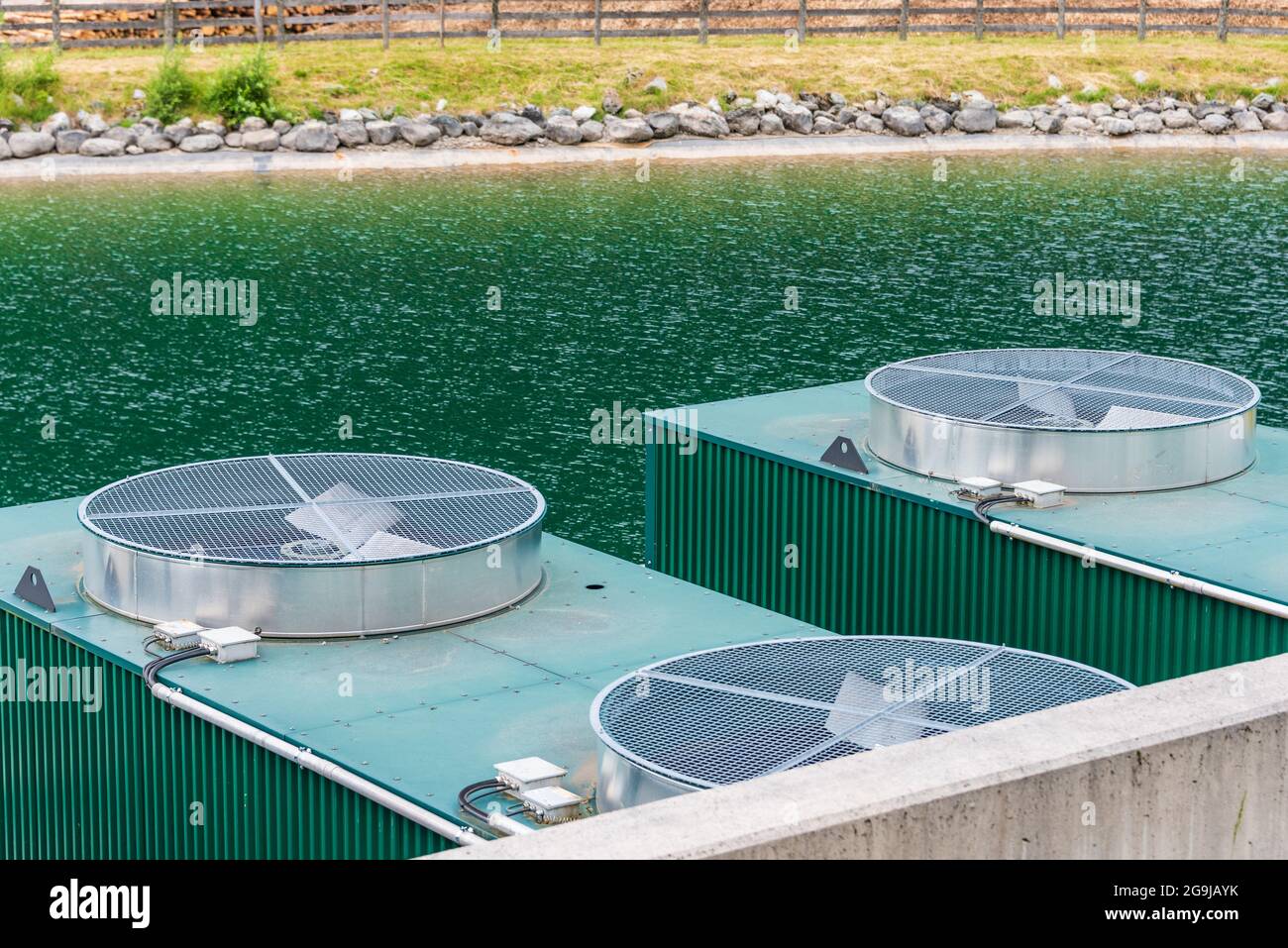 Système de refroidissement industriel. Radiateur et ventilateurs situés sur la rive du lac. Lames de rotor visibles, filet de sécurité, tuyauterie. Banque D'Images