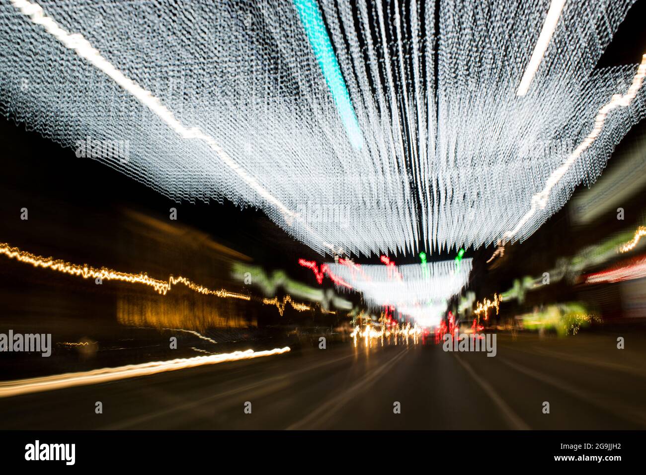 En voiture dans la ville. Pluie légère. Exposition longue durée. Une vue à travers le pare-brise pendant la conduite de nuit. Exposition longue. Artistique, abstrait. Banque D'Images