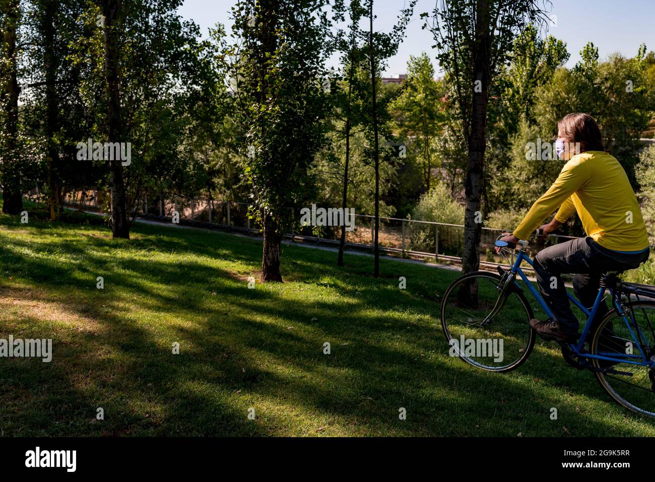 Homme portant un masque dans le parc avec sa bicyclette Banque D'Images