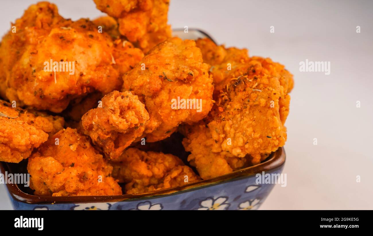 Le poulet frits épicé et croustillant s'encadre dans un bol isolé sur fond de marbre. Banque D'Images