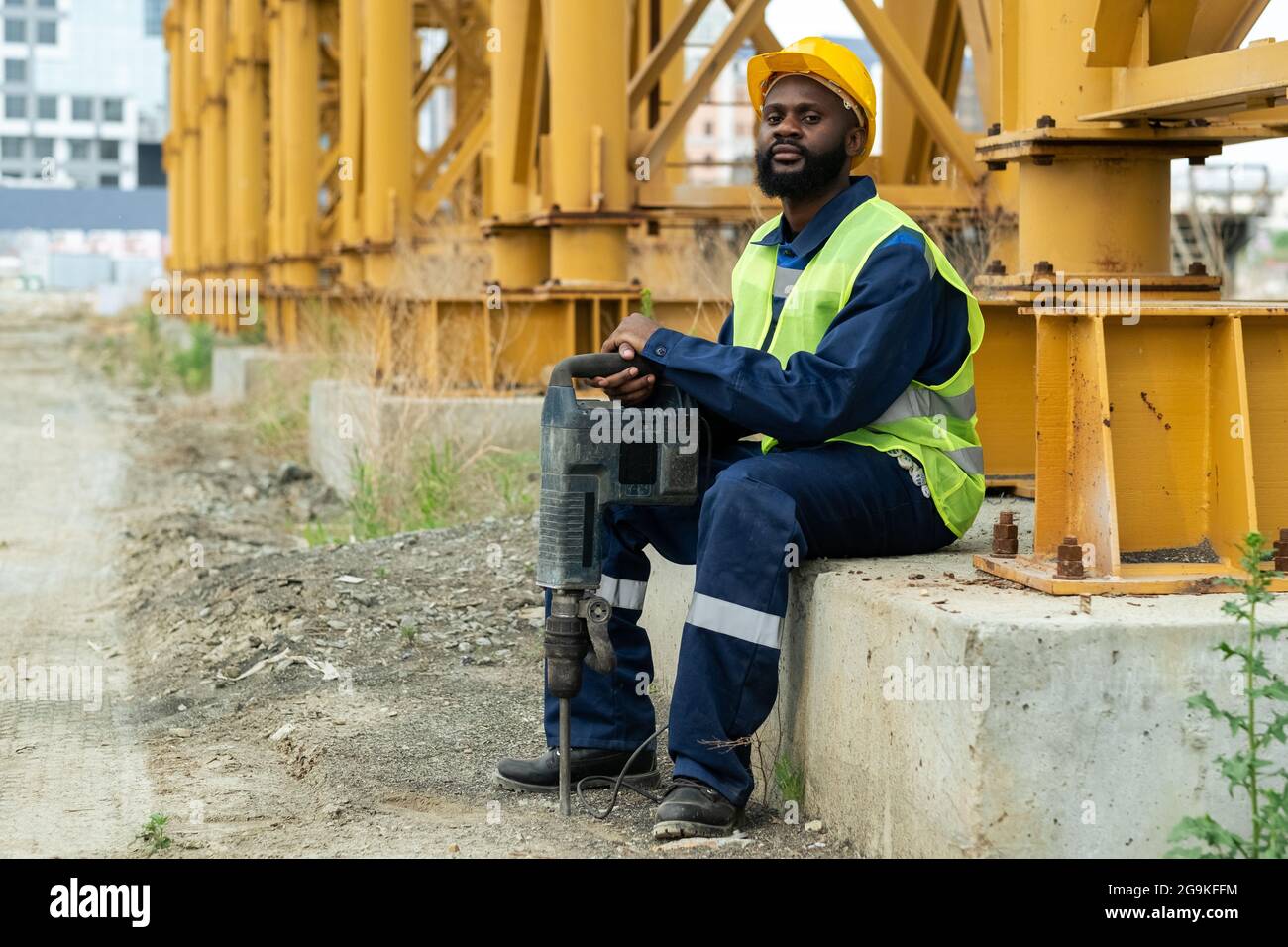 Portrait d'un ouvrier de construction africain dans un casque de travail  assis avec un driil à l'extérieur Photo Stock - Alamy