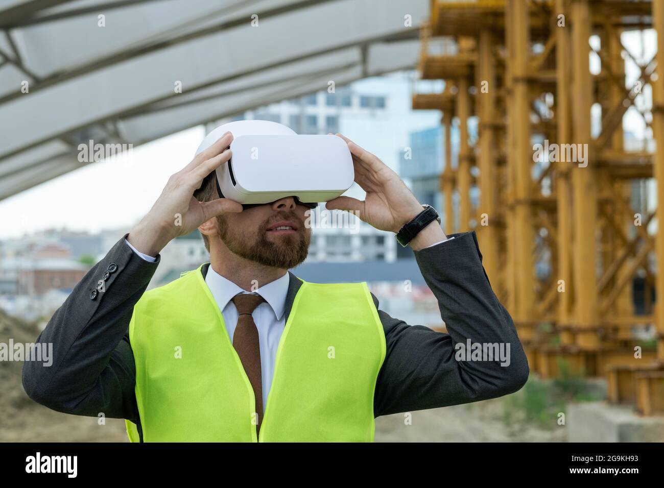 Ingénieur mature regardant le futur projet à travers les lunettes de réalité virtuelle en se tenant sur le chantier de construction Banque D'Images