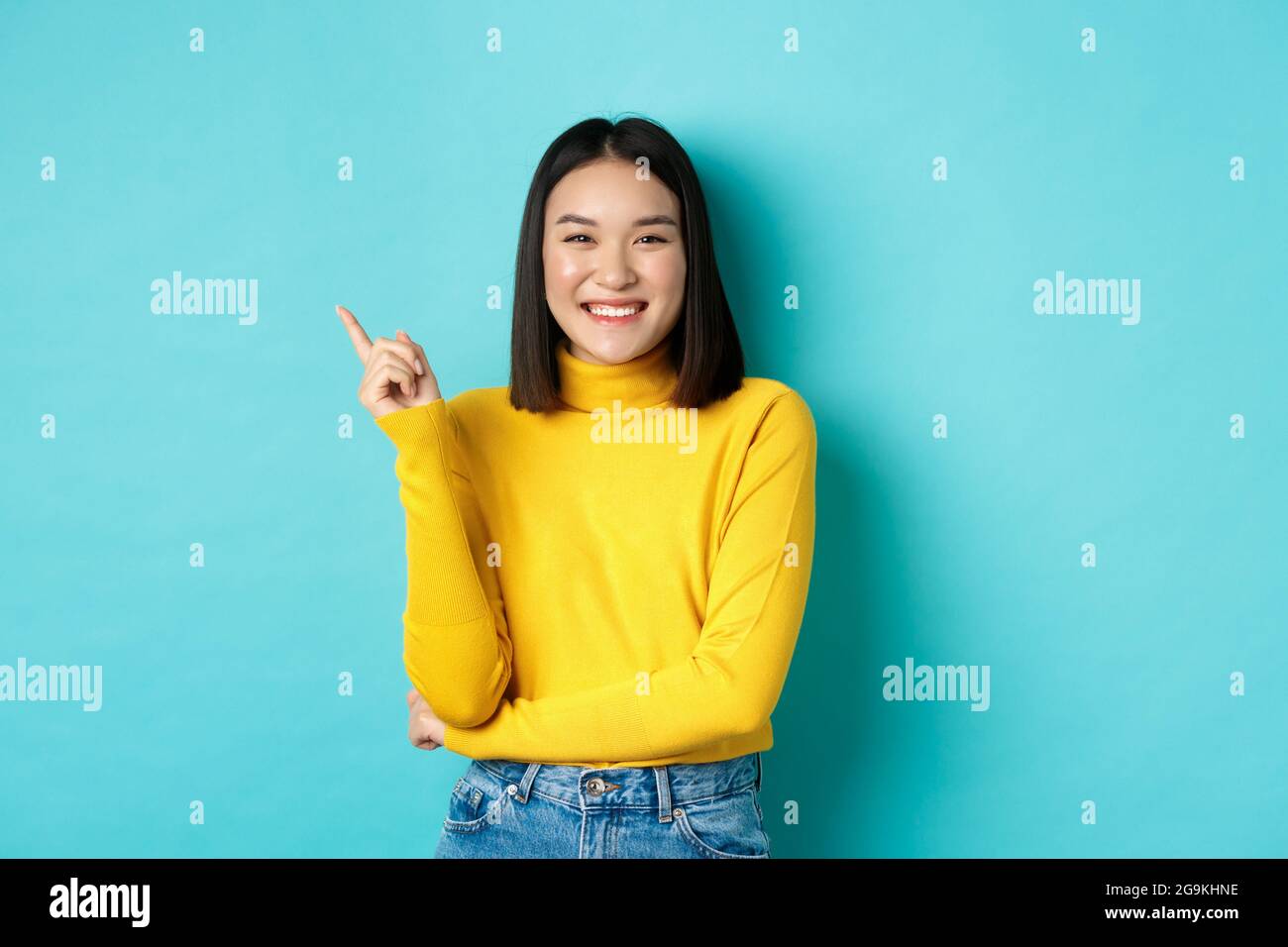 Image De La Belle Jeune Femme Asiatique Avec Un Sourire Parfait Et Aucune Tache Sur La Peau Pointant Le Doigt Vers La Gauche Regardant Satisfait Se Tenant Sur Le Dos Bleu Photo