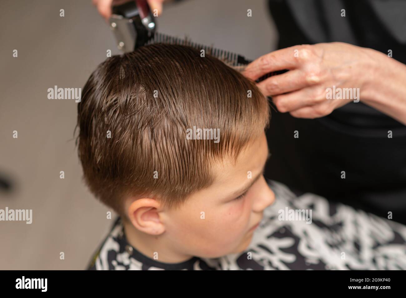 Couper les cheveux d'un jeune garçon dans un salon de beauté. Main avec  l'instrument utilisé pour couper les cheveux.mains du coiffeur tenant un  peigne et des ciseaux colorés.Cl Photo Stock - Alamy