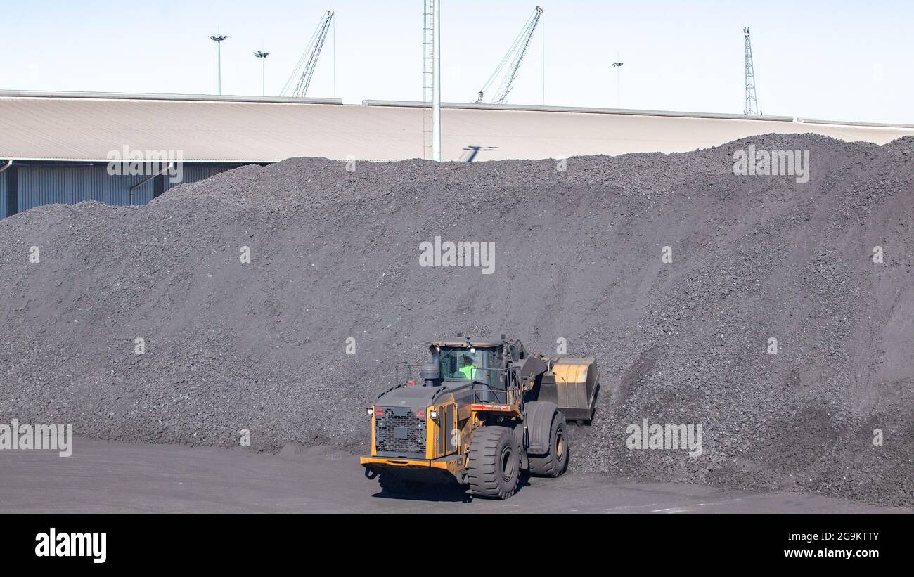 Tas de matières premières de produit de charbon industriel avec machine de terrassement lourde avec bac à godet de pelle pour le chargement dans les camions. Banque D'Images