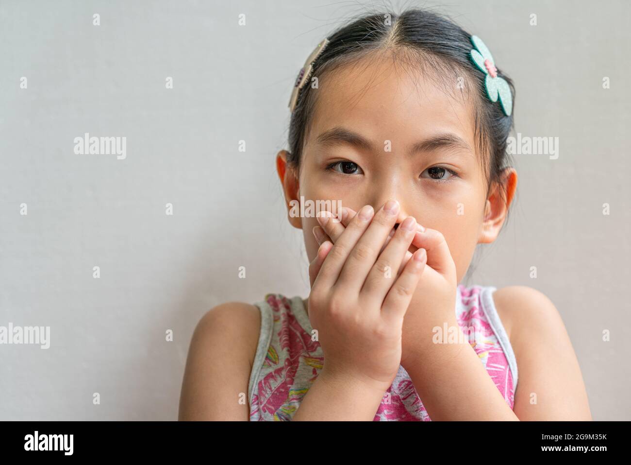 Portrait En Gros Plan De Petite Fille Asiatique Avec Des Cheveux Longs Noirs Attaches Couvrant Sa Bouche Avec Deux Mains Photo Stock Alamy