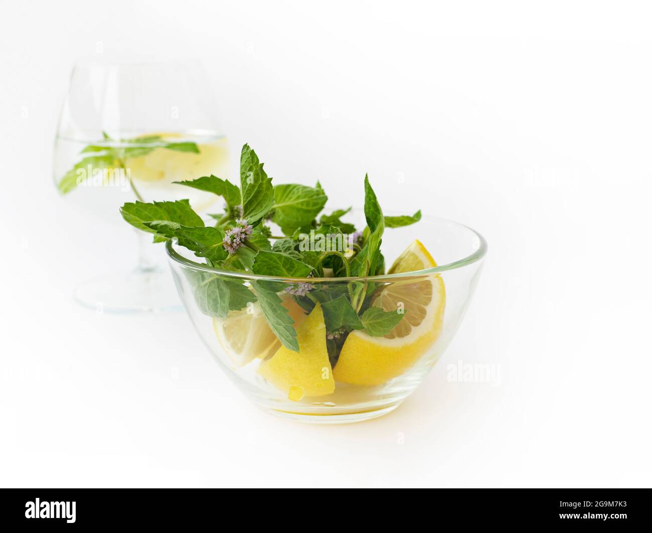 Verre à vin avec bol en verre d'eau Detox avec feuilles de menthe fraîche et quartiers de citron. Thème de la santé. Antioxydants nutraceutiques. Banque D'Images