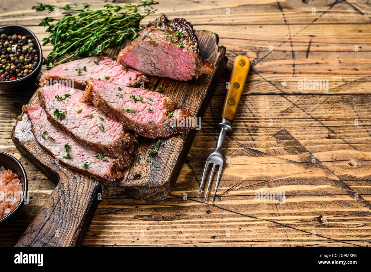 Tranches rares de rôti de boeuf sirloin à trois pointes steak bbq sur une planche à découper en bois. fond en bois. Vue de dessus. Copier l'espace Banque D'Images