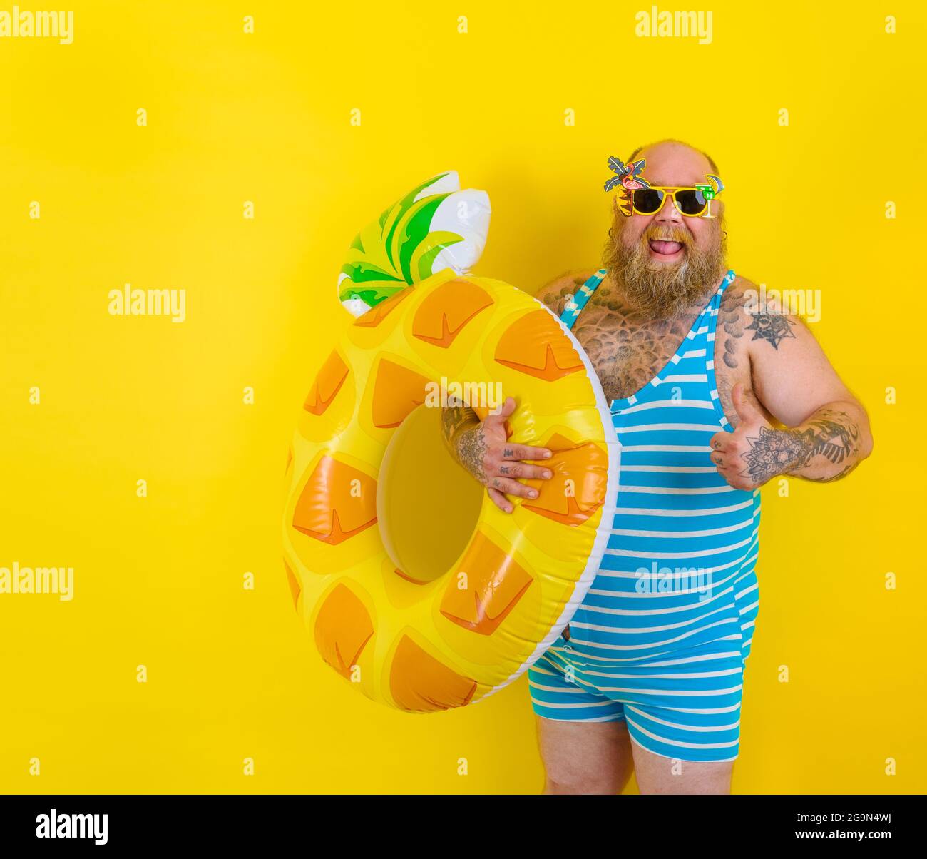 FAT Happy man avec perruque dans la tête est prêt à nager avec un donut sauvetage Banque D'Images