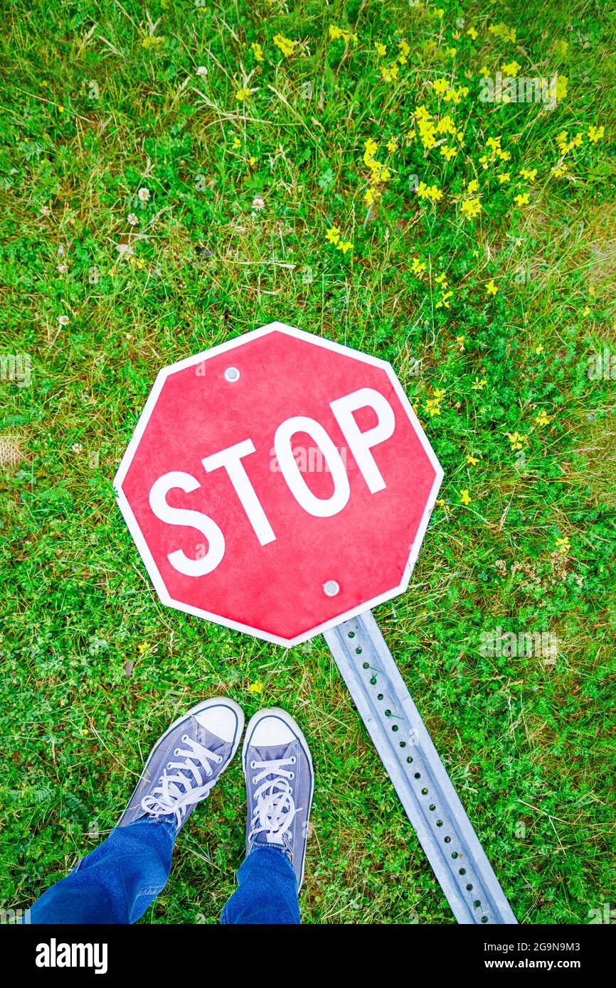 Pieds selfie avec signe d'arrêt sur fond d'herbe verte Banque D'Images