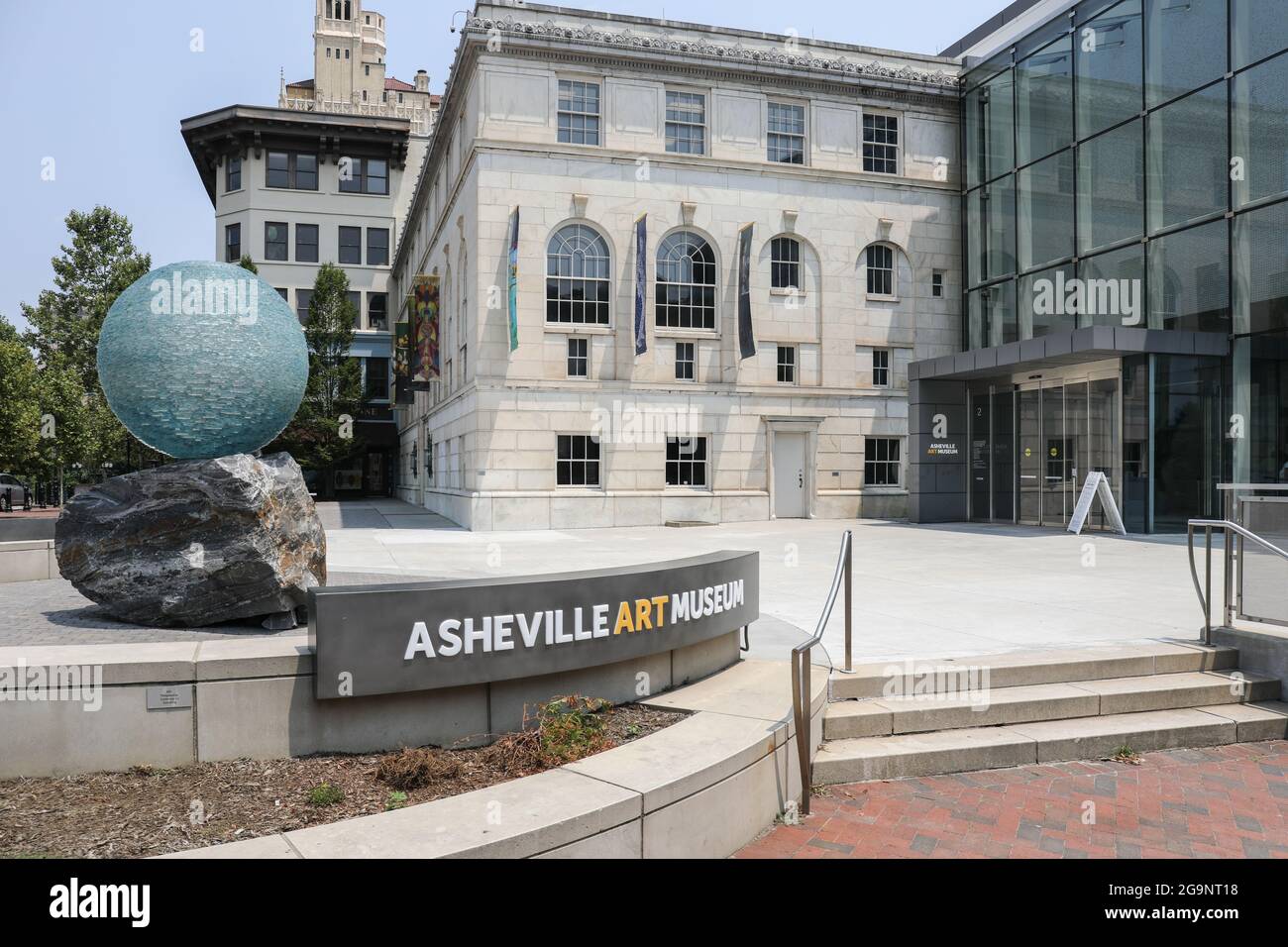 ASHEVILLE, NC, USA-22 JUILLET 2021 : le musée d'art d'Asheville, montrant l'entrée du bâtiment, l'espace public, le panneau, et la sculpture de boule de verre et de roche. Banque D'Images