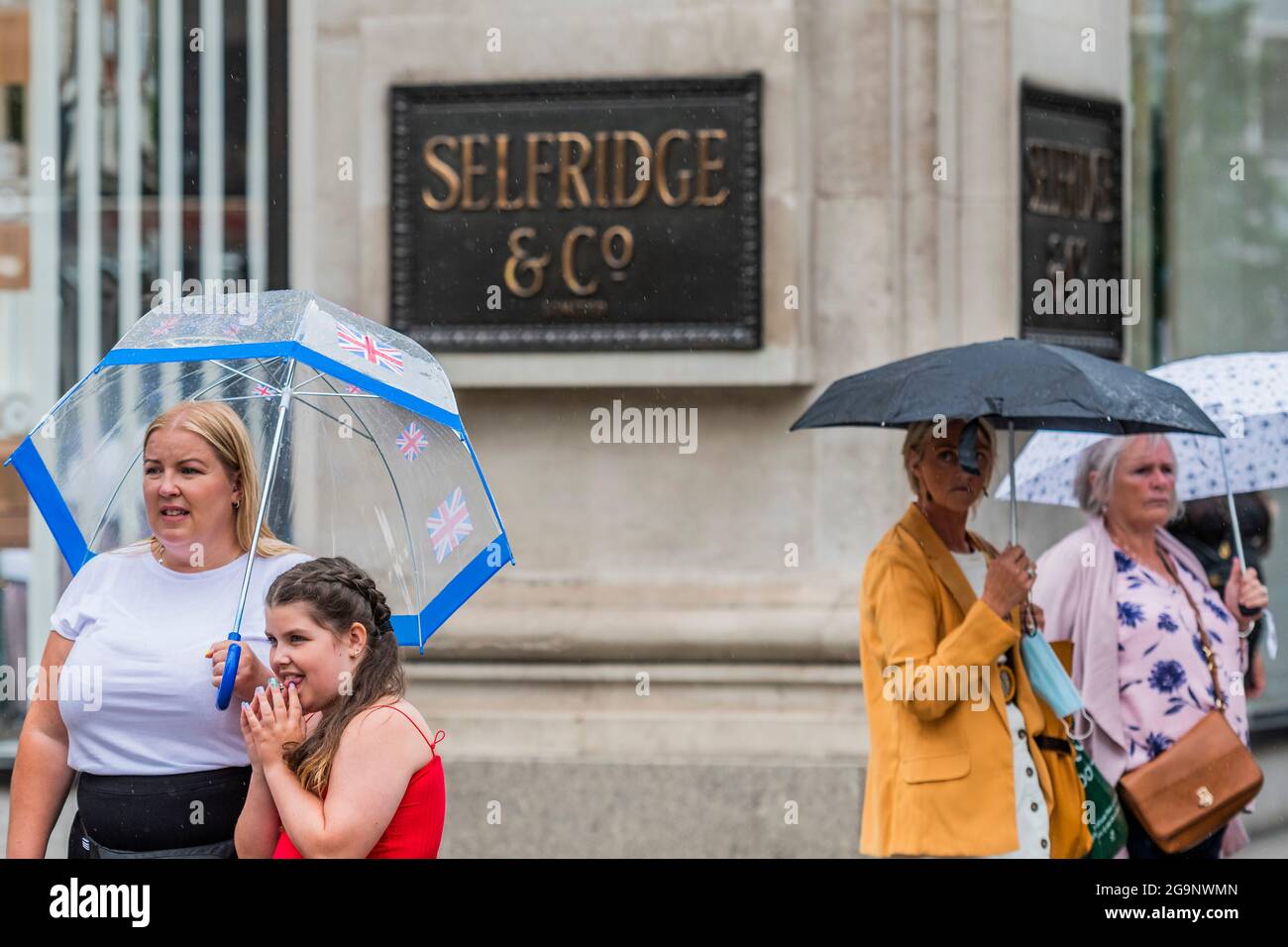 Londres, Royaume-Uni. 27 juillet 2021. Se protéger d'une tempête peut également être approprié, car la pluie tombe sur les acheteurs - "faire du foin pendant que le soleil brille" est un slogan sur les fenêtres de Selfridges qui a été mis en vente au plus offrant. Crédit : Guy Bell/Alay Live News Banque D'Images