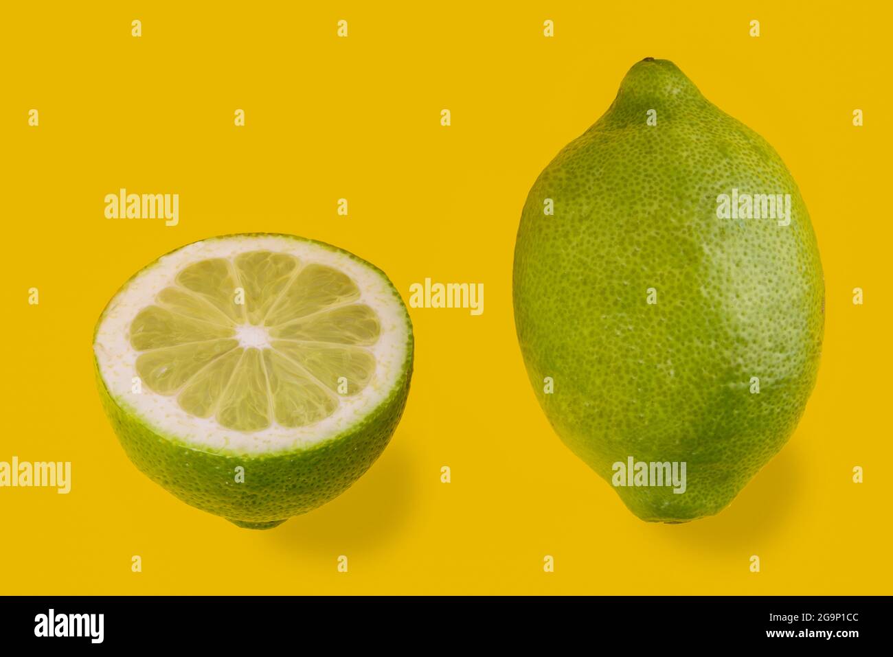 Citron vert de Syracuse, Sicile, Italie, variété femminello, un fruit entier et un demi coupé isolé sur fond jaune, espace de copie Banque D'Images