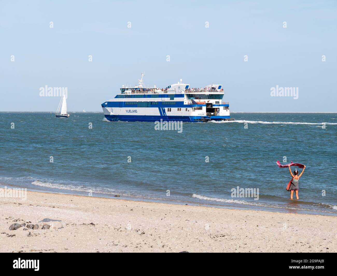 Une femme agitant Au revoir à des passagers sur un ferry partant du port de l'île de Frise occidentale Vlieland traversant Waddensea à Harlingen, pays-Bas Banque D'Images