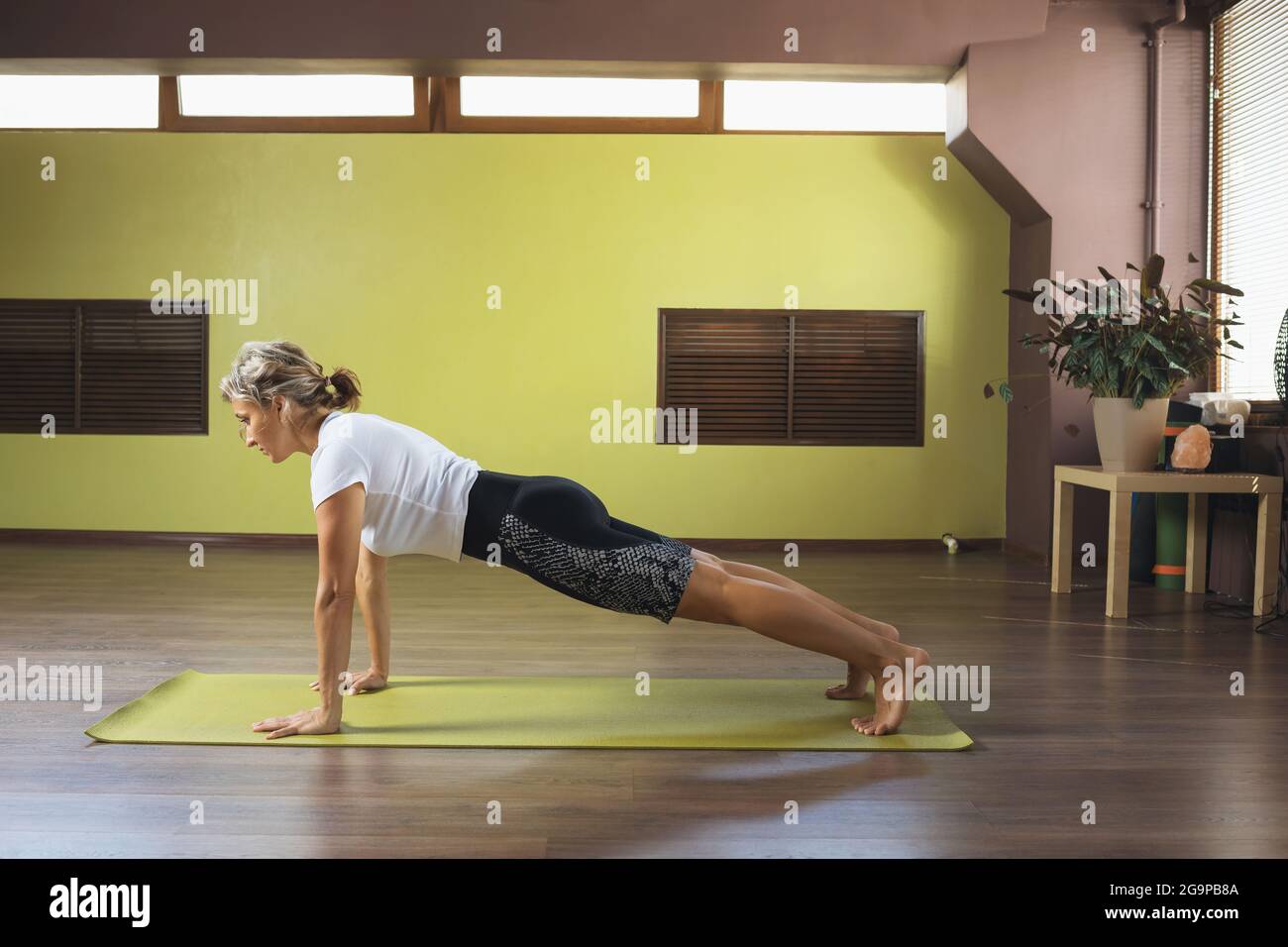 Une femme sportive pratiquant le yoga effectue un exercice de phalakasana, une pose de planche en studio Banque D'Images