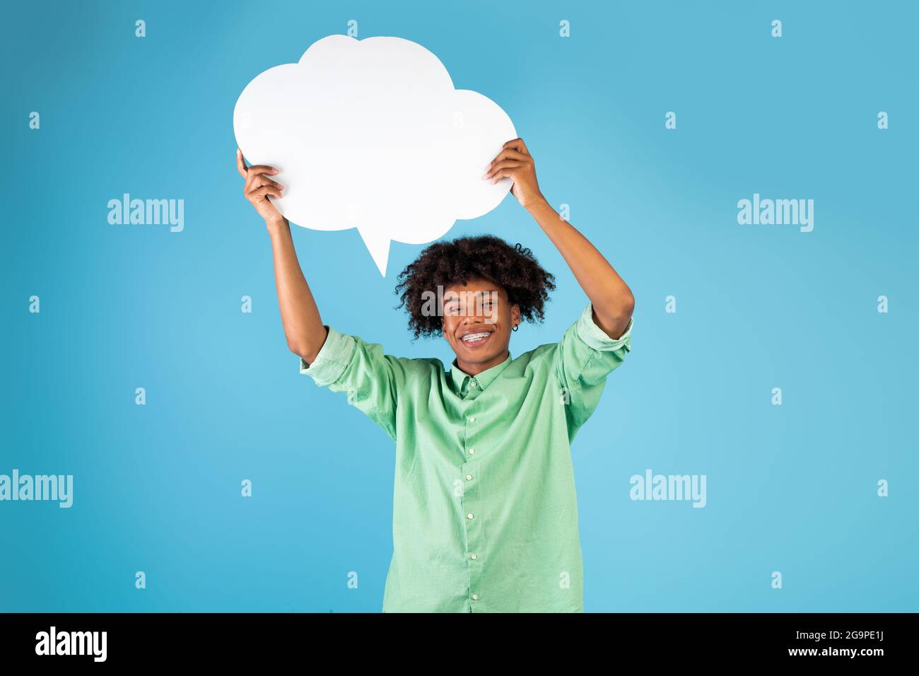 Un adolescent afro-américain positif tenant une bulle vide de discours au-dessus de sa tête sur fond bleu, mockup Banque D'Images