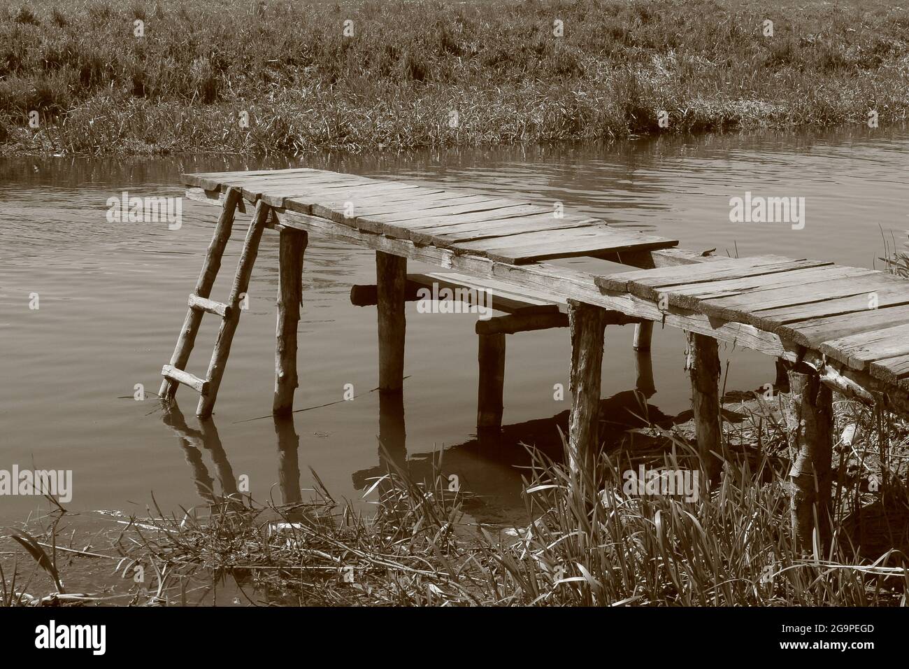 photo monochrome ancienne de l'étang du village et du pont en bois Banque D'Images