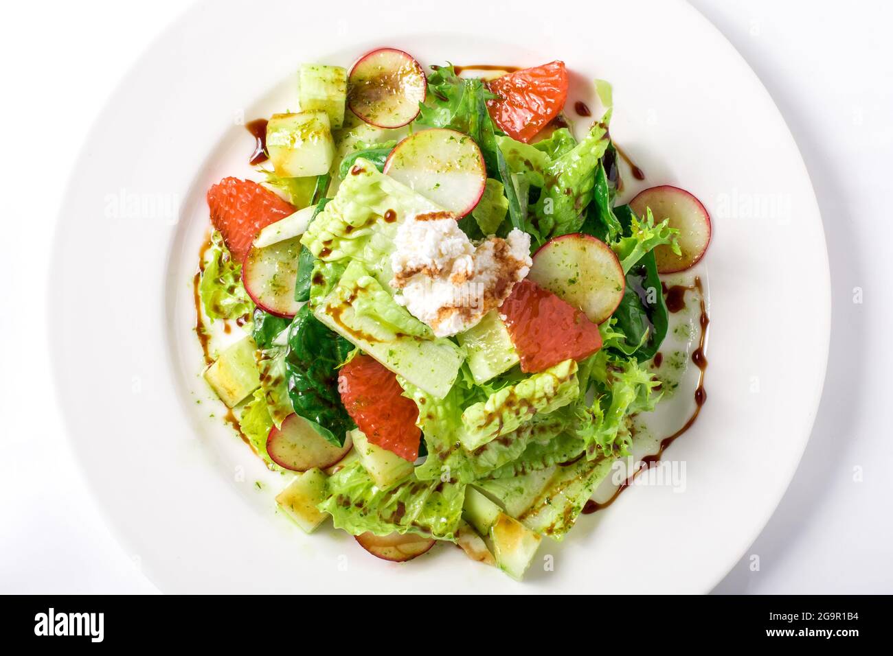 Salade fraîche avec laitue, radis, pamplemousse, fromage et vinaigrette aux agrumes dans une assiette blanche. Vue du dessus gros plan Banque D'Images