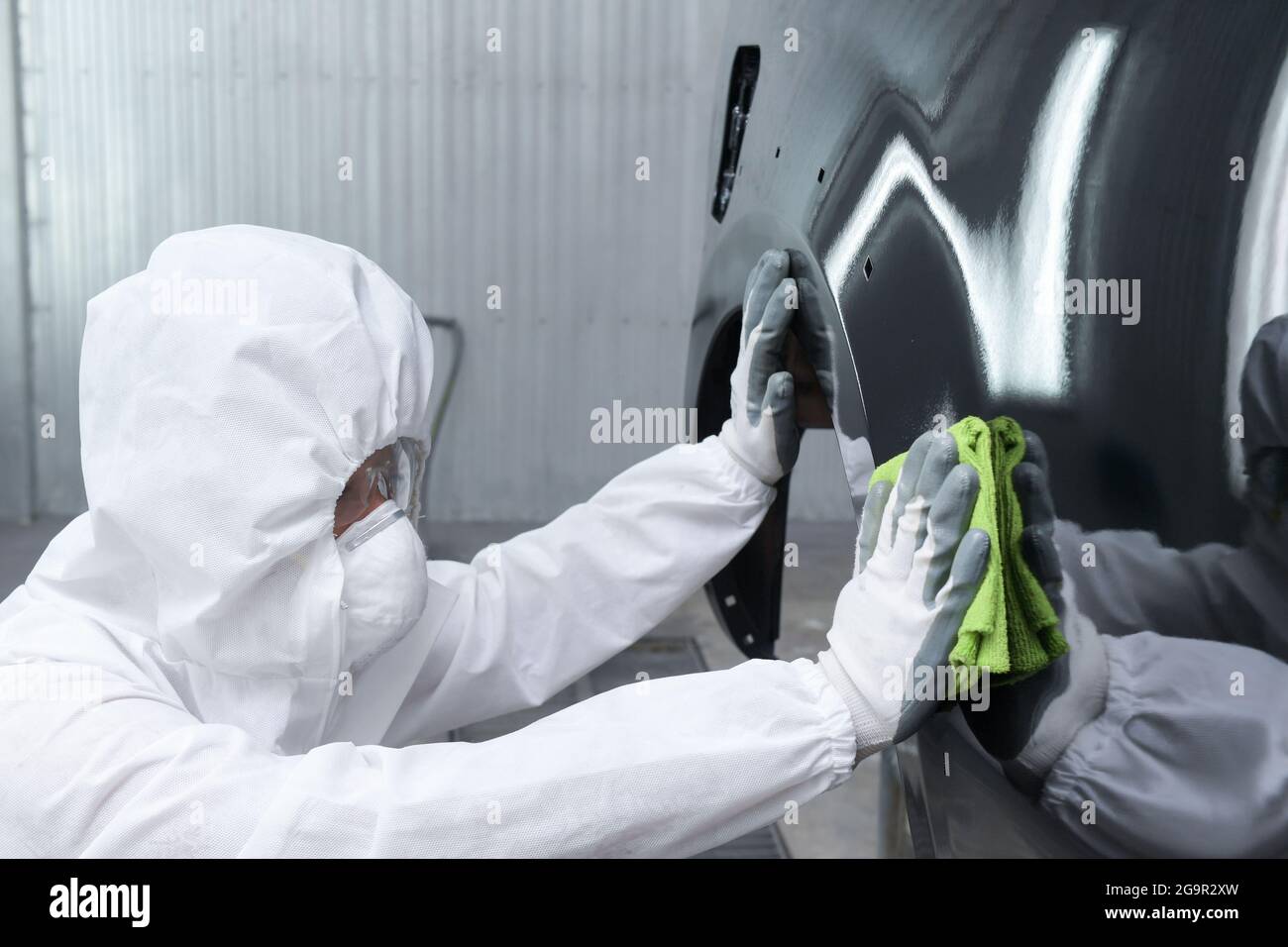 Homme sur une voiture de lavage de polissage de voiture avec une machine à polir.habillage de voiture - mains avec polisseur orbital dans l'atelier de réparation automobile. Mise au point sélective. Banque D'Images