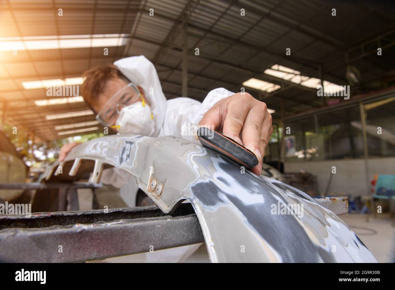Homme sur une voiture de lavage de polissage de voiture avec une machine à polir.habillage de voiture - mains avec polisseur orbital dans l'atelier de réparation automobile. Mise au point sélective. Banque D'Images