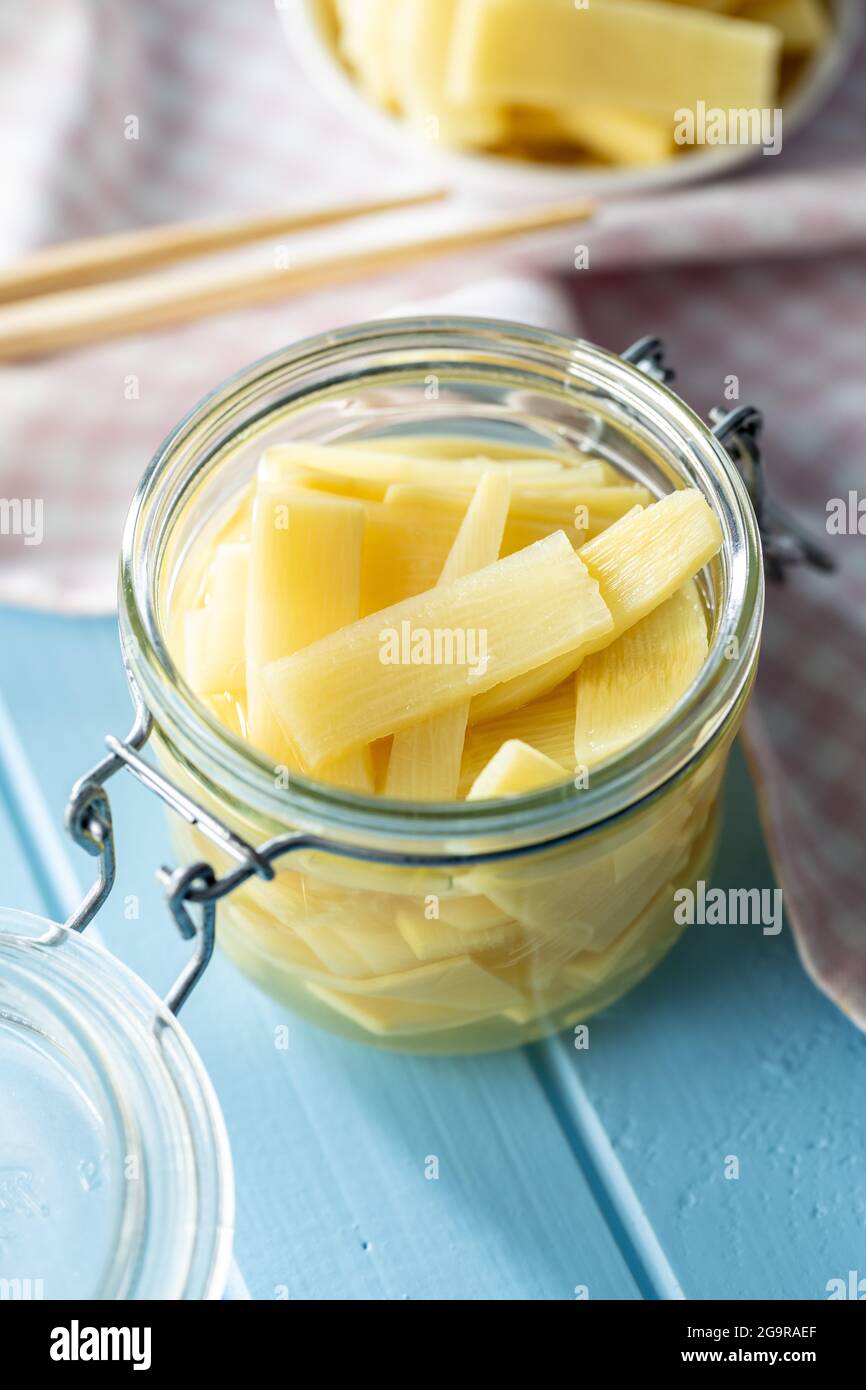 Tranches de pousses de bambou en conserve dans un pot sur une table bleue. Banque D'Images