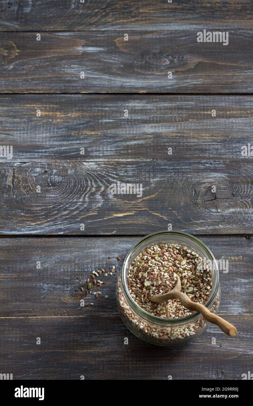 Mélange de céréales pour des craquelins keto sains de graines de chia, de lin, de sésame, de graines de citrouille moulues dans un pot en verre sur fond de bois Banque D'Images