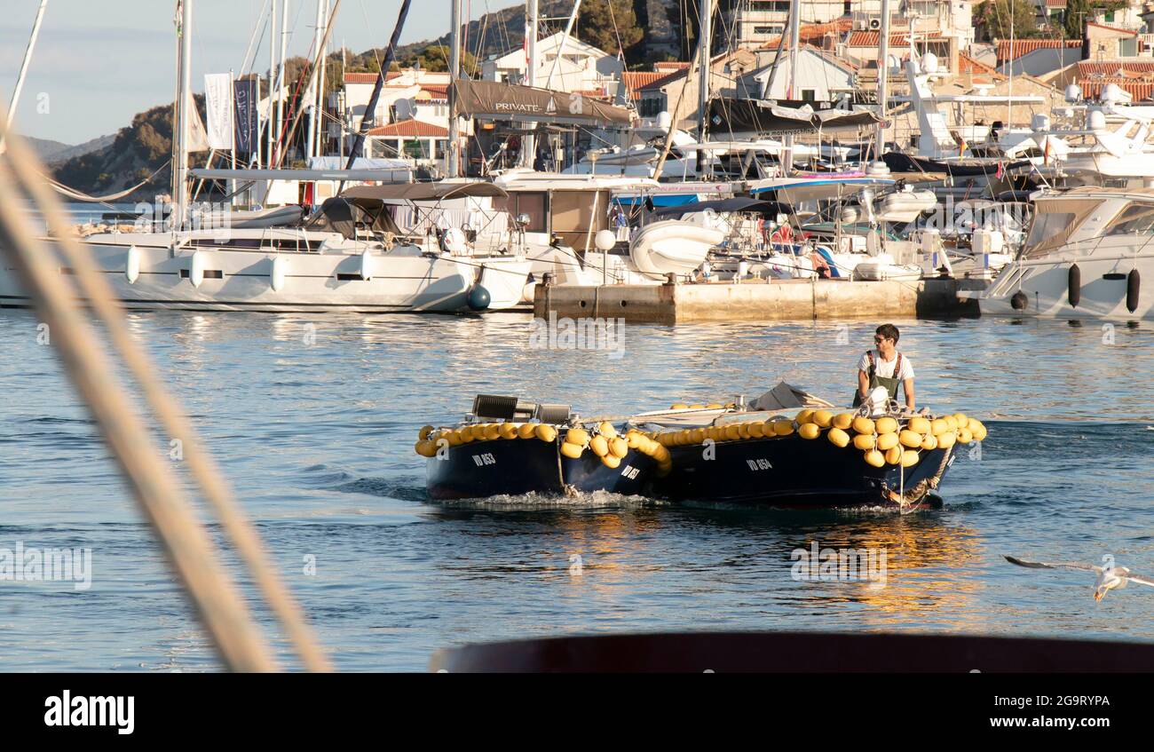 Tribunj, Croatie - 1 juillet 2021 : homme à la tête d'un bateau de pêche avec bouées d'aile jaunes le jour d'été, près du port Banque D'Images