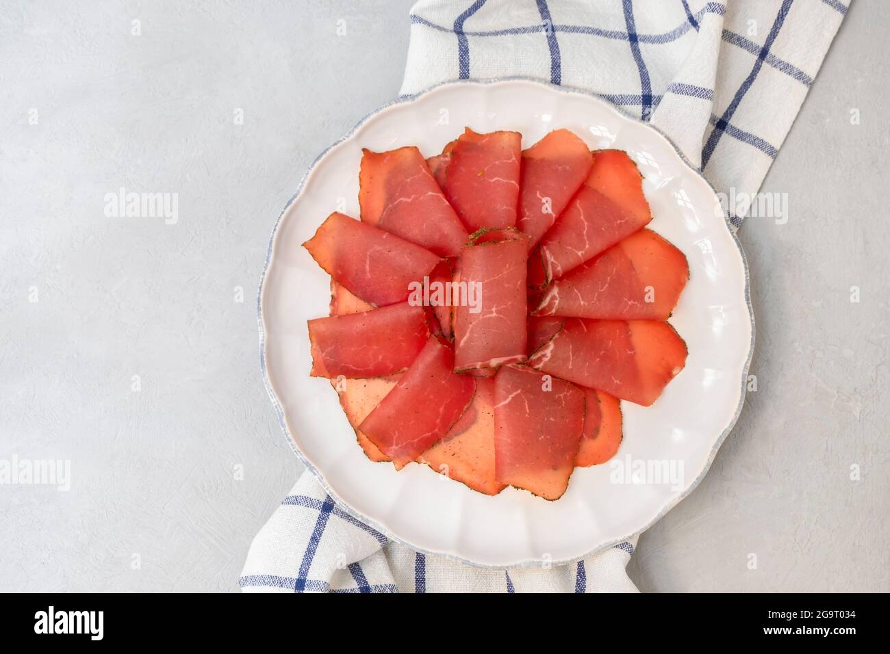 Morceaux de bœuf saccadés. Viande de bœuf séchée sur plaque blanche, vue du dessus, plat avec espace de copie Banque D'Images