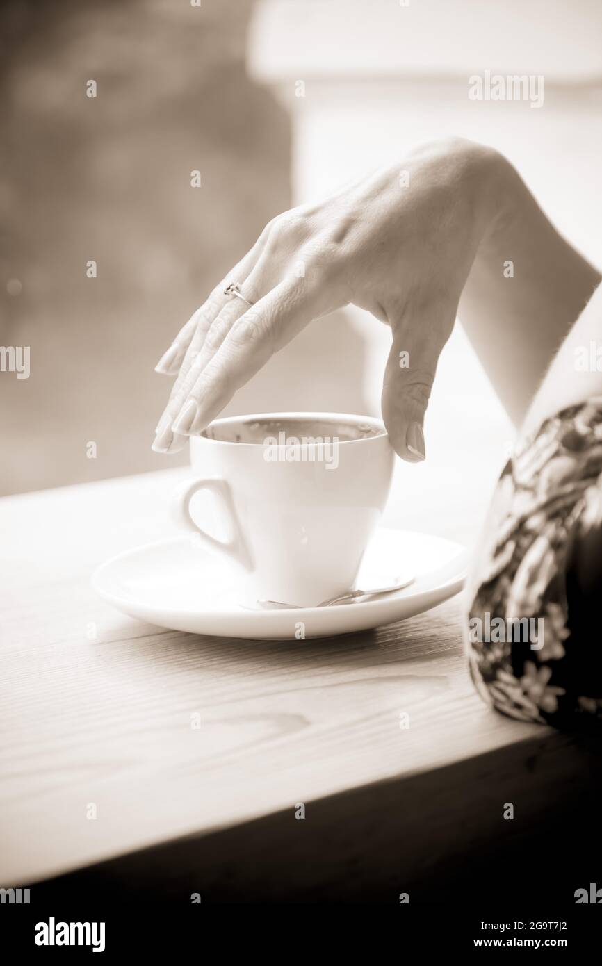 Une main gracieuse femelle tient une tasse de café. Prise de vue en noir et  blanc Photo Stock - Alamy