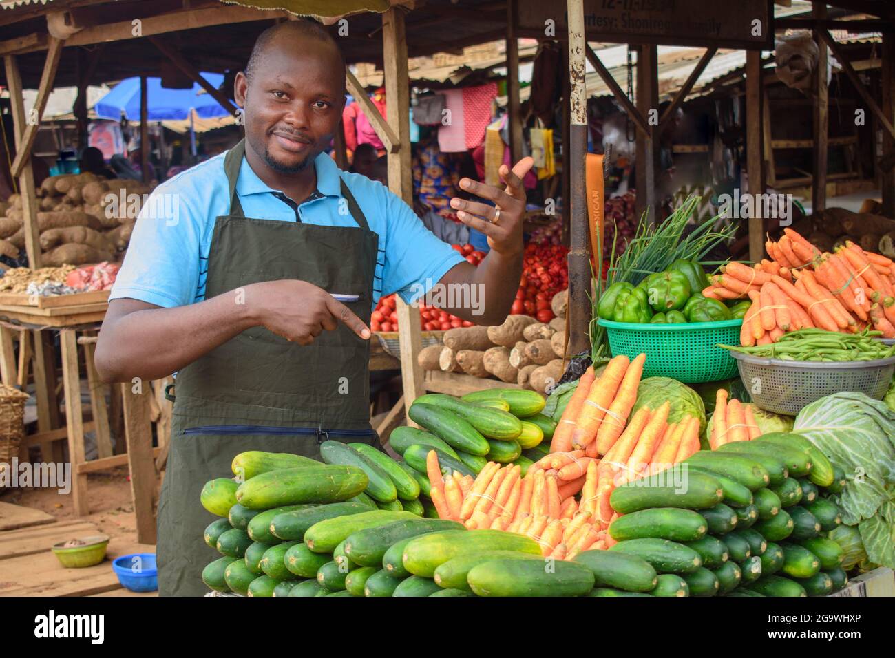 Photo de stock d'un homme d'alimentation africain ou d'un homme d'affaires avec un tablier, debout à sa stalle dans un marché, prêt à vendre à des clients Banque D'Images