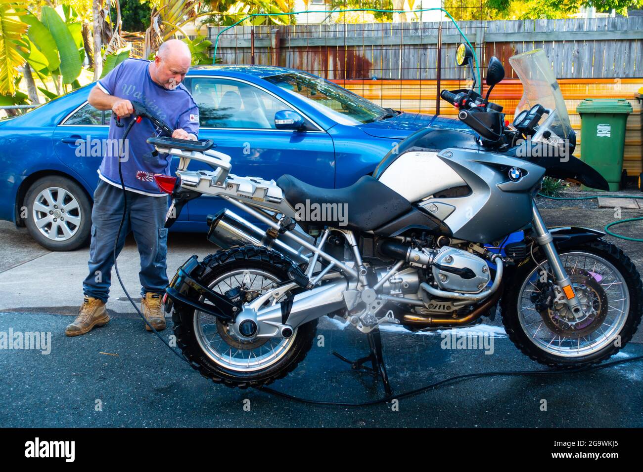 Homme nettoyant sa moto BMW R1200 GS avec un tuyau d'eau haute pression. Banque D'Images