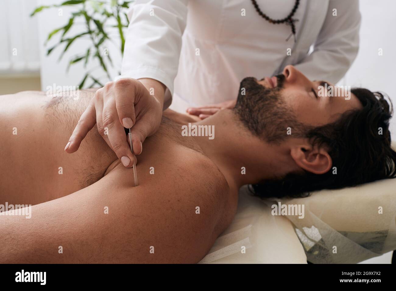 médecin faisant une ponction avec une aiguille d'acupuncture un point sur l'épaule du patient pour traiter la douleur et les blessures. Médecine traditionnelle chinoise, acupuncture Banque D'Images