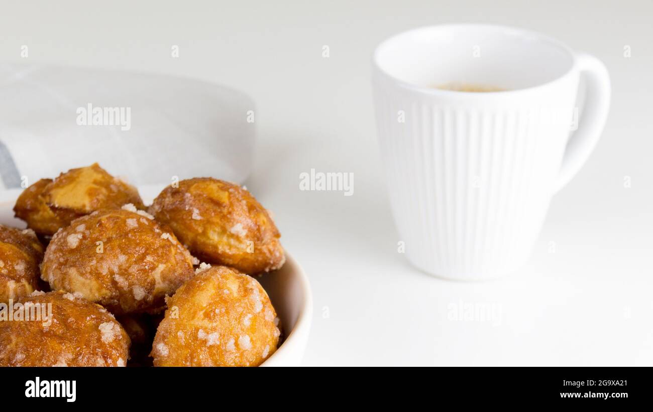 poupettes françaises avec perles de sucre sur l'assiette avec une tasse de café blanc. Pâte de choux boulangeries françaises classiques. Banque D'Images