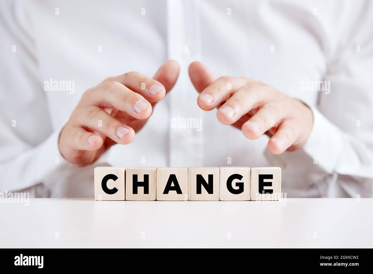 Homme d'affaires tient ses mains de manière protective sur les cubes de bois avec le mot change. Gestion du changement dans l'entreprise ou changement de concept de style de vie. Banque D'Images