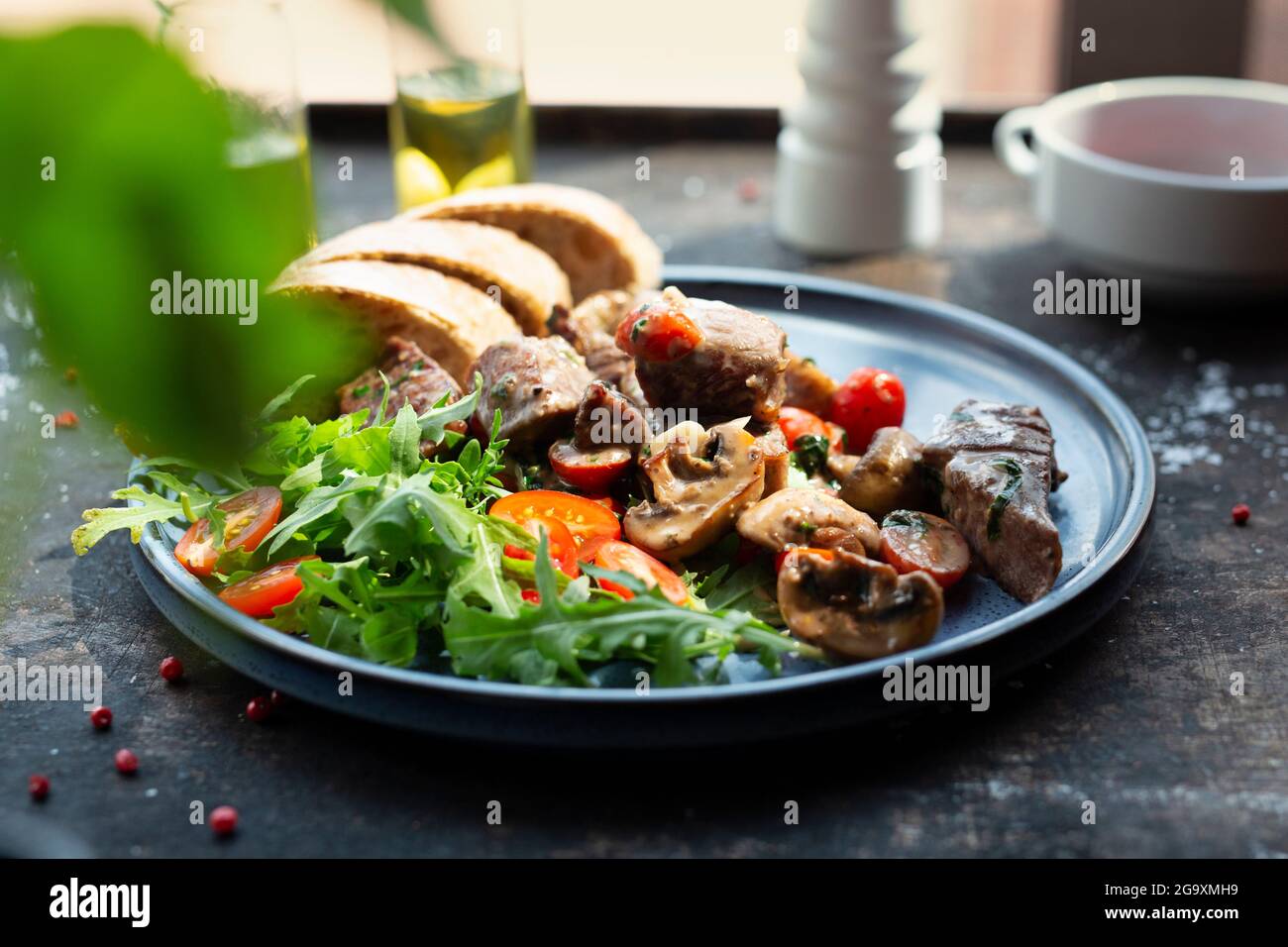 Ragoût de foie avec champignons et tomates cerises, servi avec du pain et de la salade fraîche. Le cuisinier cuisine et sert un plat appétissant. Le service de plats finis Banque D'Images