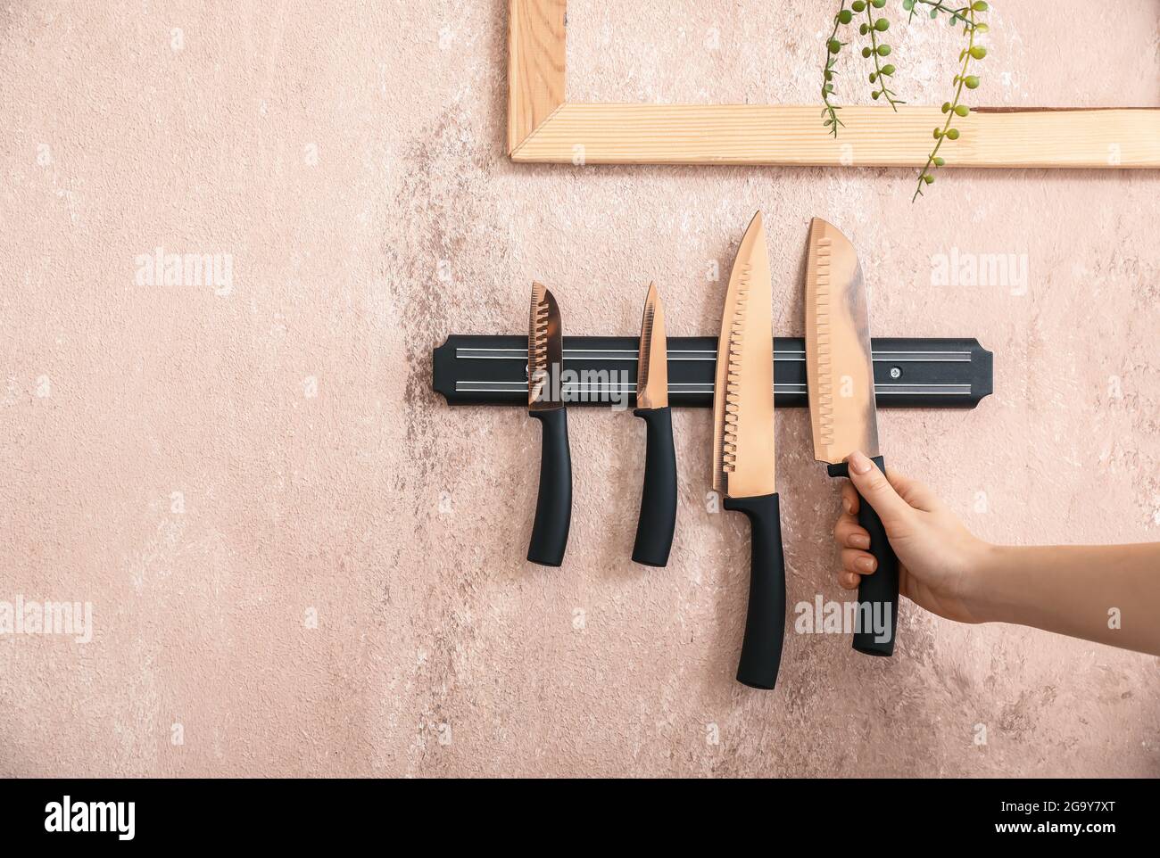 Femme et support magnétique avec couteaux accrochés au mur de couleur Banque D'Images