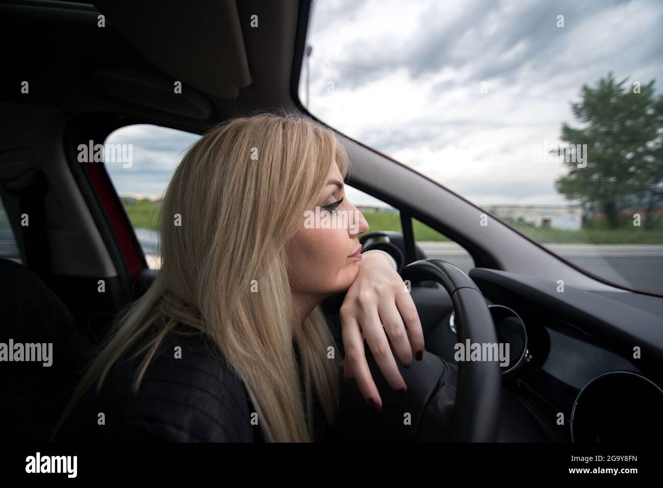 Une femme s'est penchée sur un volant dans une voiture dans un embouteillage Banque D'Images