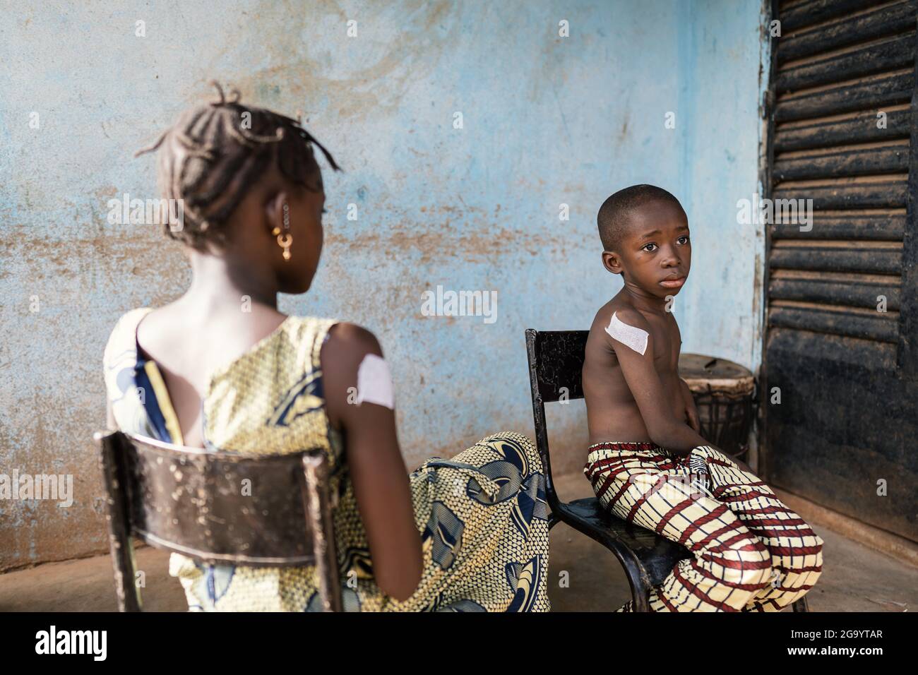 Dans cette image, deux enfants noirs, une fille qui la tourne vers l'appareil photo et un garçon avec une expression painée sur son visage, sont assis à l'extérieur d'une zone rurale Banque D'Images
