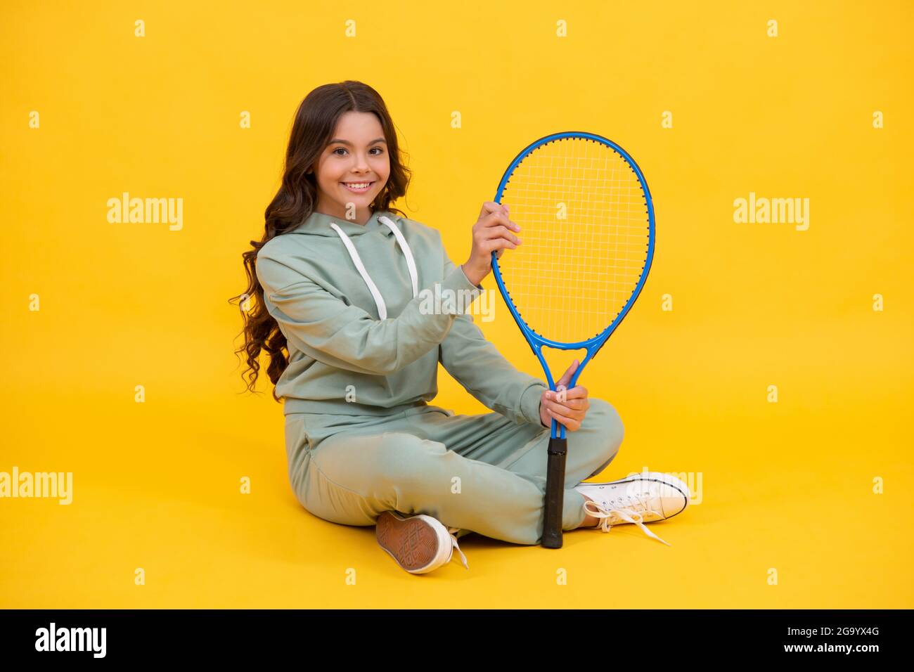 enfant dans les vêtements de sport tenir raquette. enfant avec raquette. jeune fille se détendre après l'entraînement sportif. Banque D'Images