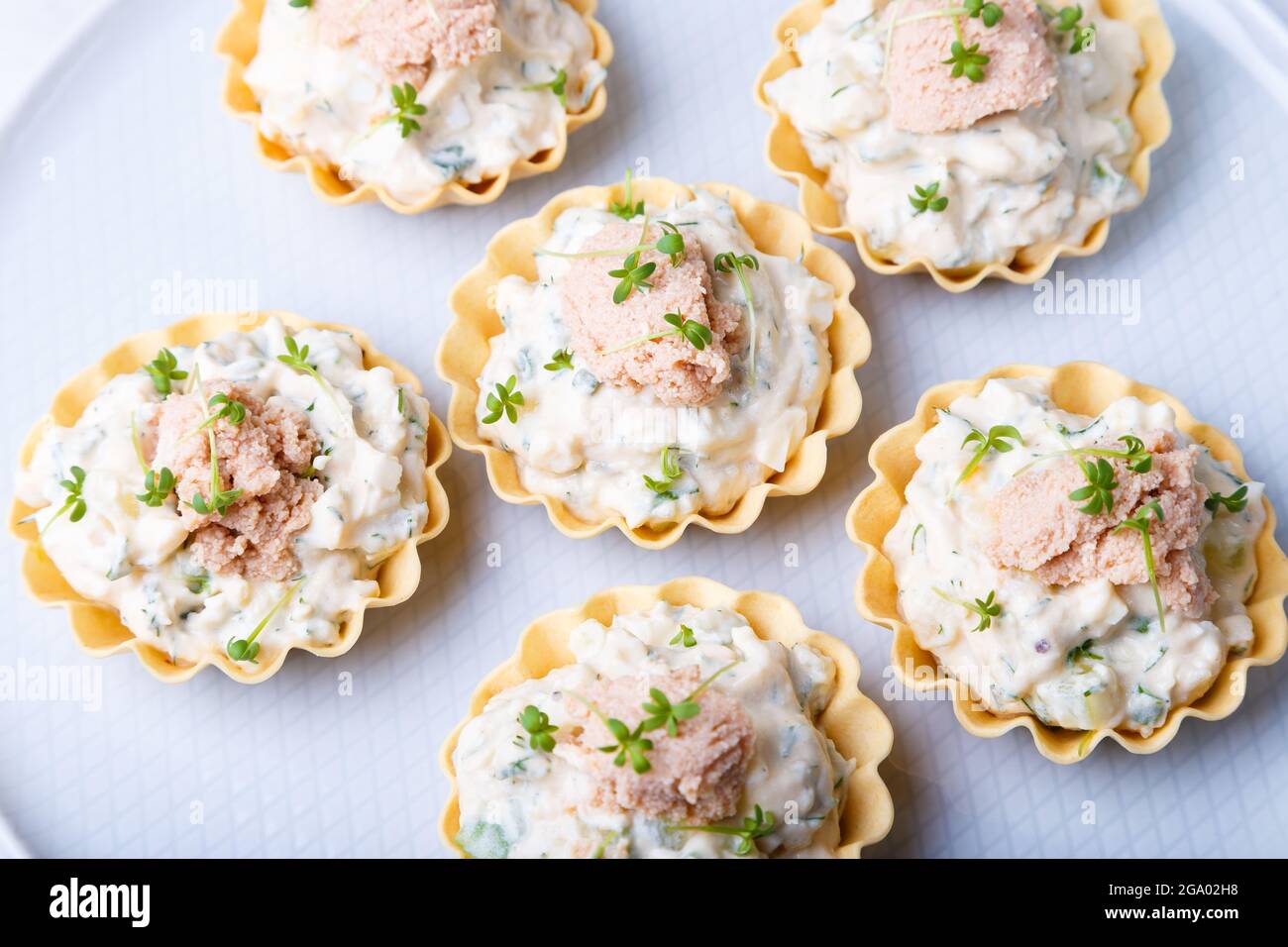 Tartelettes farcies au foie de morue, au caviar de morue, au concombre et aux microverts. Hors-d'œuvre traditionnel en portions froides dans un panier à pâtisseries. Gros plan, haut Banque D'Images