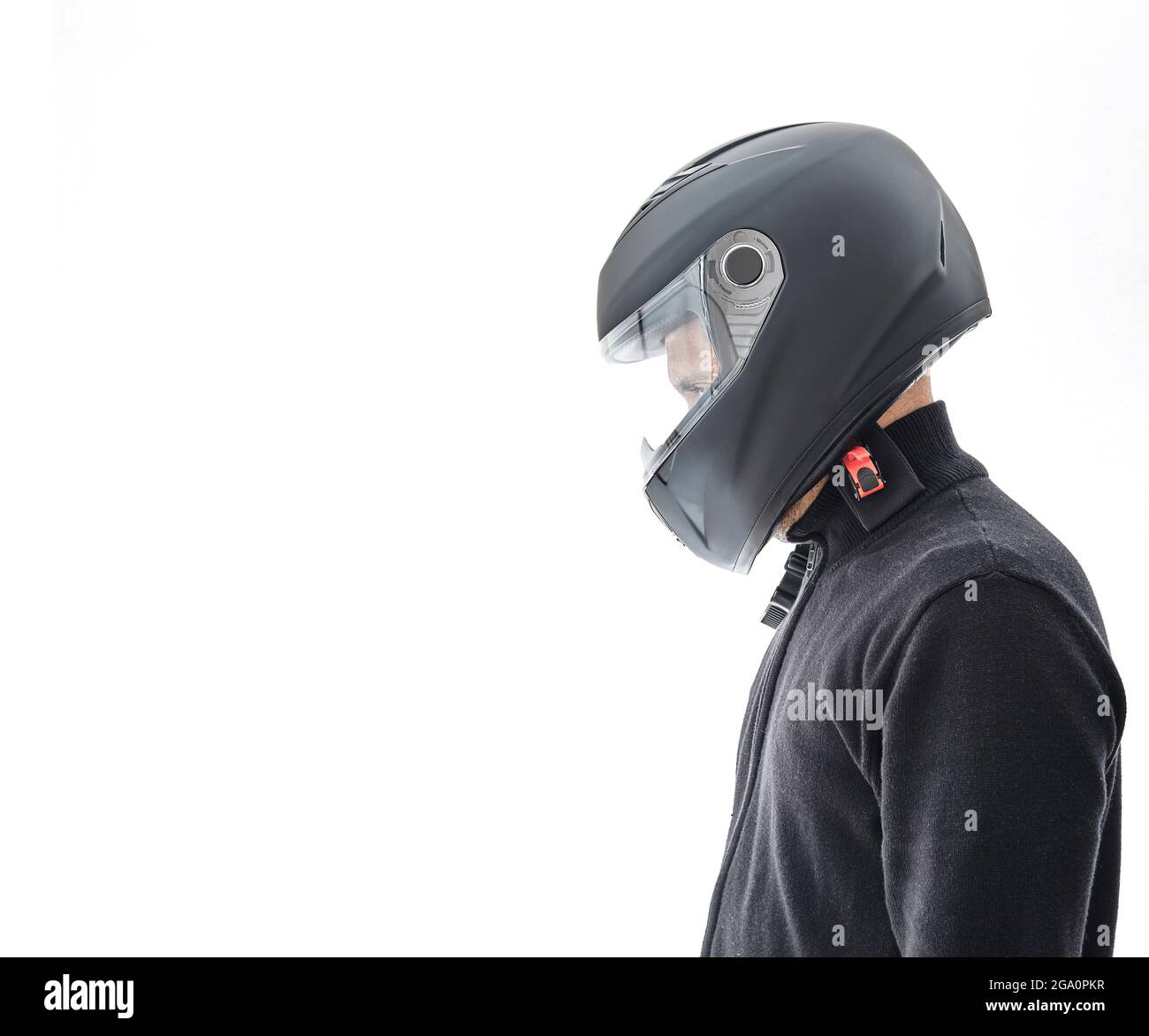 Portrait d'un homme avec une veste à carreaux noirs et un casque de moto qui prétend conduire la moto, isolé sur un mur blanc de studio. Banque D'Images
