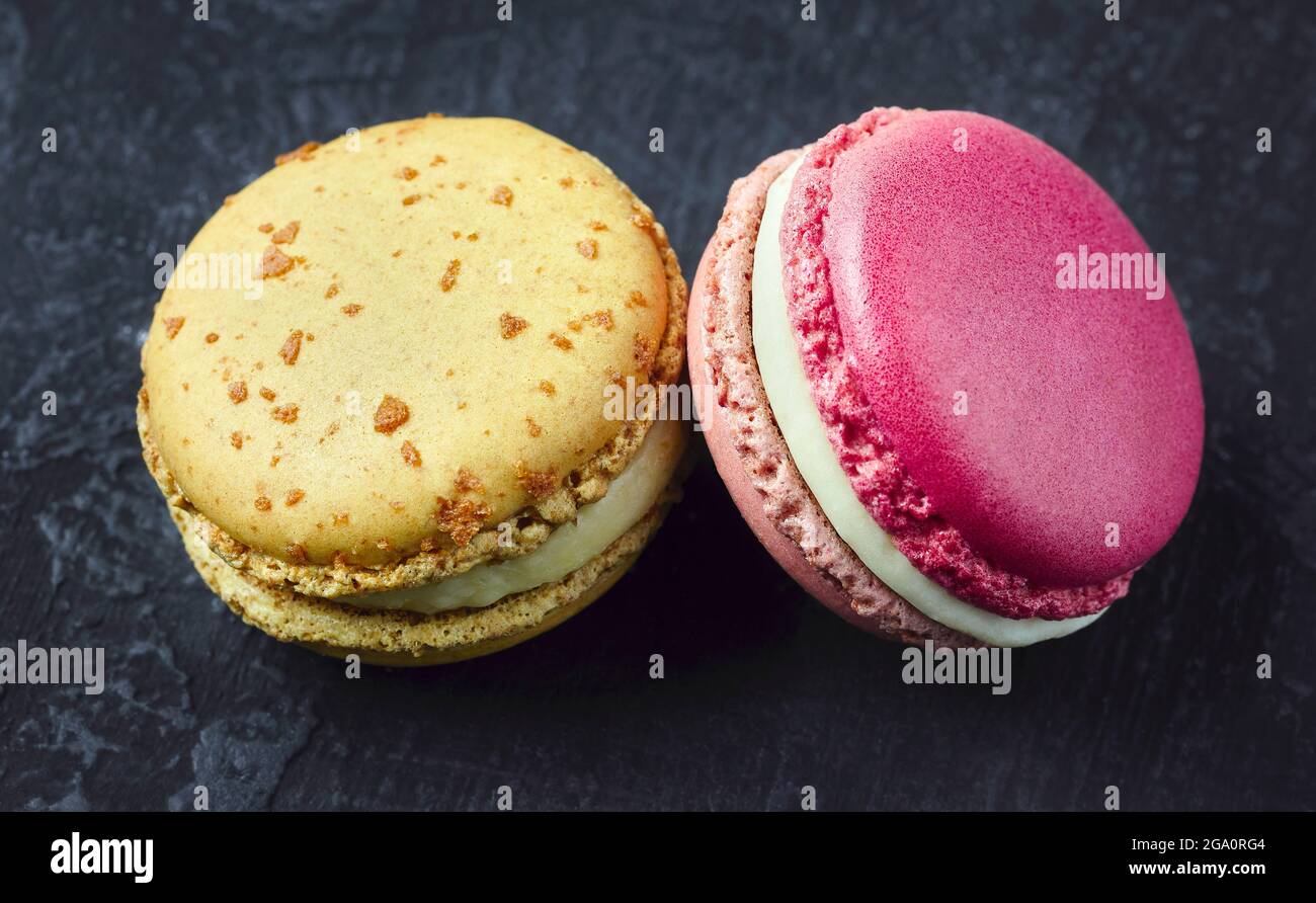 Deux doux macarons français sur fond sombre. Banque D'Images