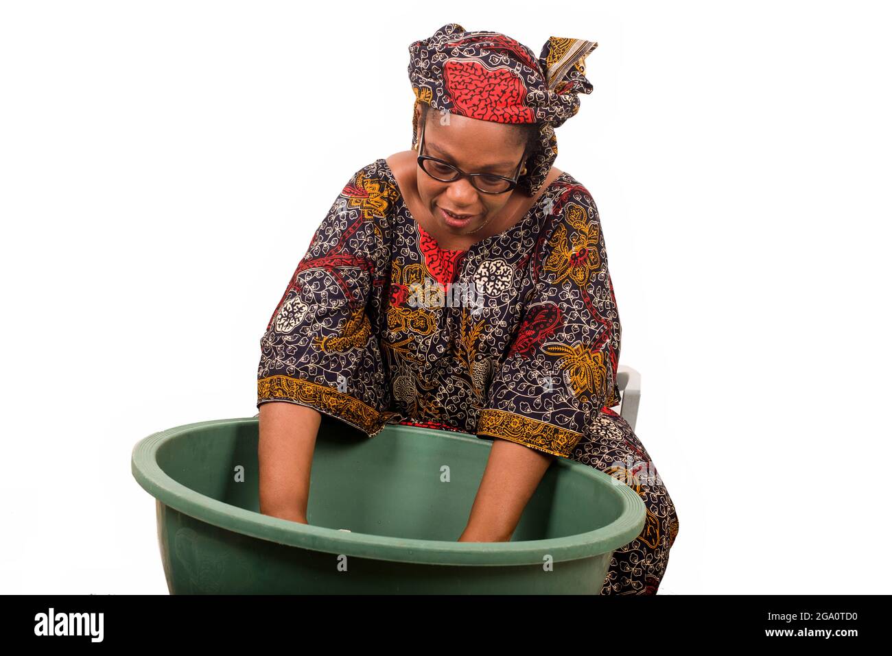 femme africaine mûre en toile de longe assis faisant du linge. Banque D'Images
