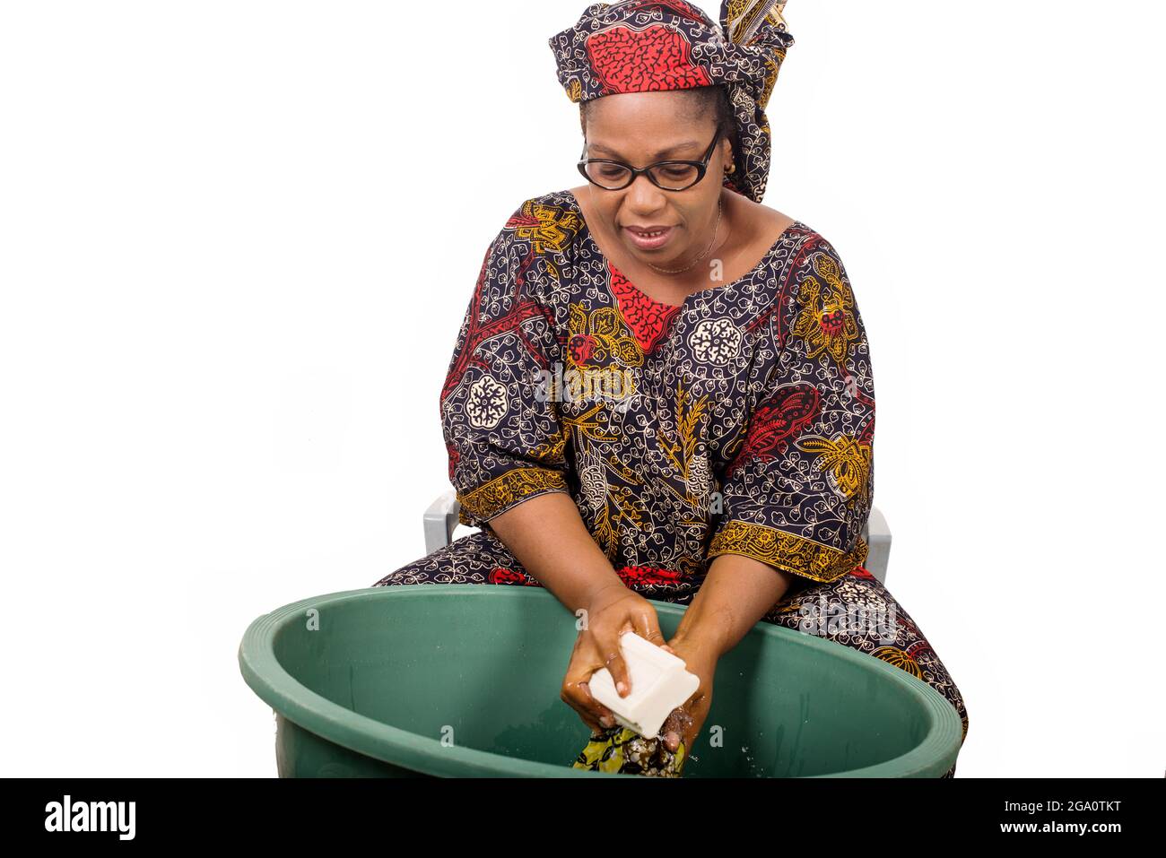 femme africaine mûre en toile de longe assis faisant du linge. Banque D'Images