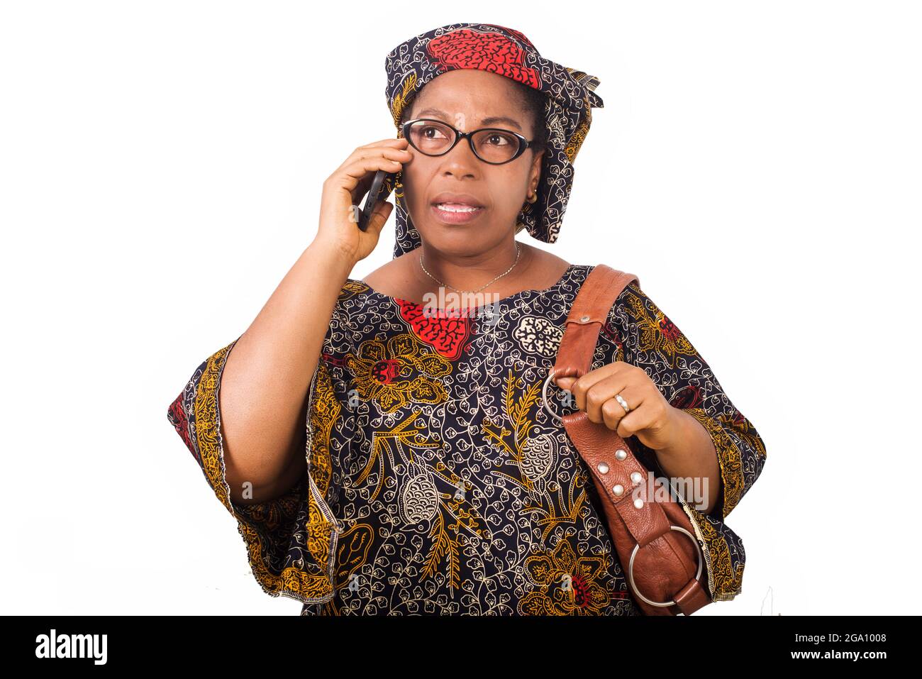 femme africaine mûre en toile de longe sur fond blanc communiquant avec le téléphone mobile. Banque D'Images