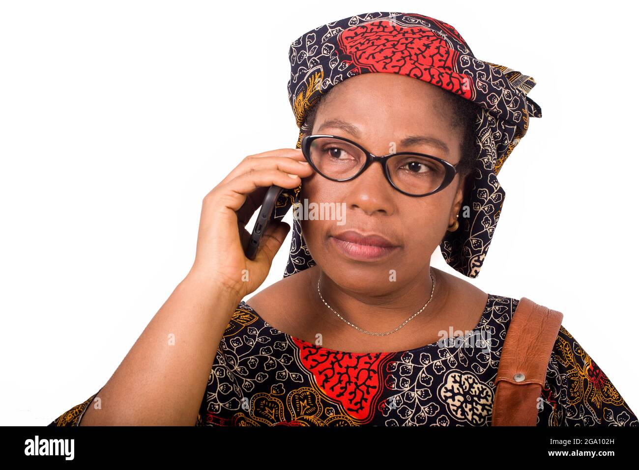 femme africaine mûre en toile de longe sur fond blanc communiquant avec le téléphone mobile. Banque D'Images