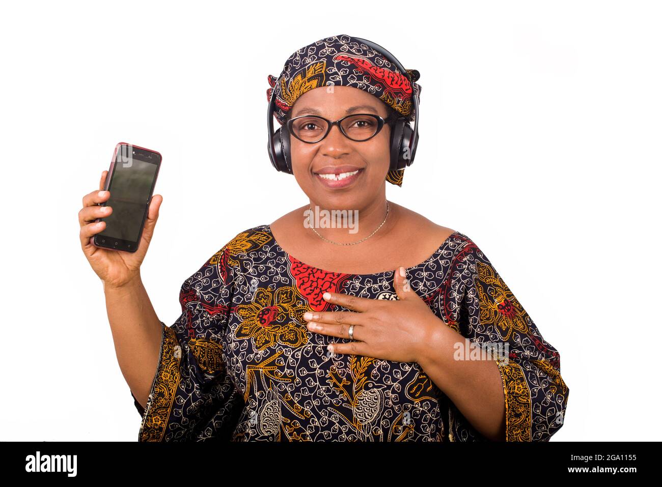 femme africaine mûre en loincloth écoutant de la musique à l'aide d'écouteurs et de téléphone portable ayant le geste de la main Banque D'Images