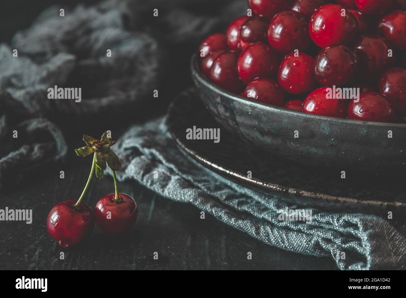 Cerises mûres dans un bol noir sur fond noir Banque D'Images