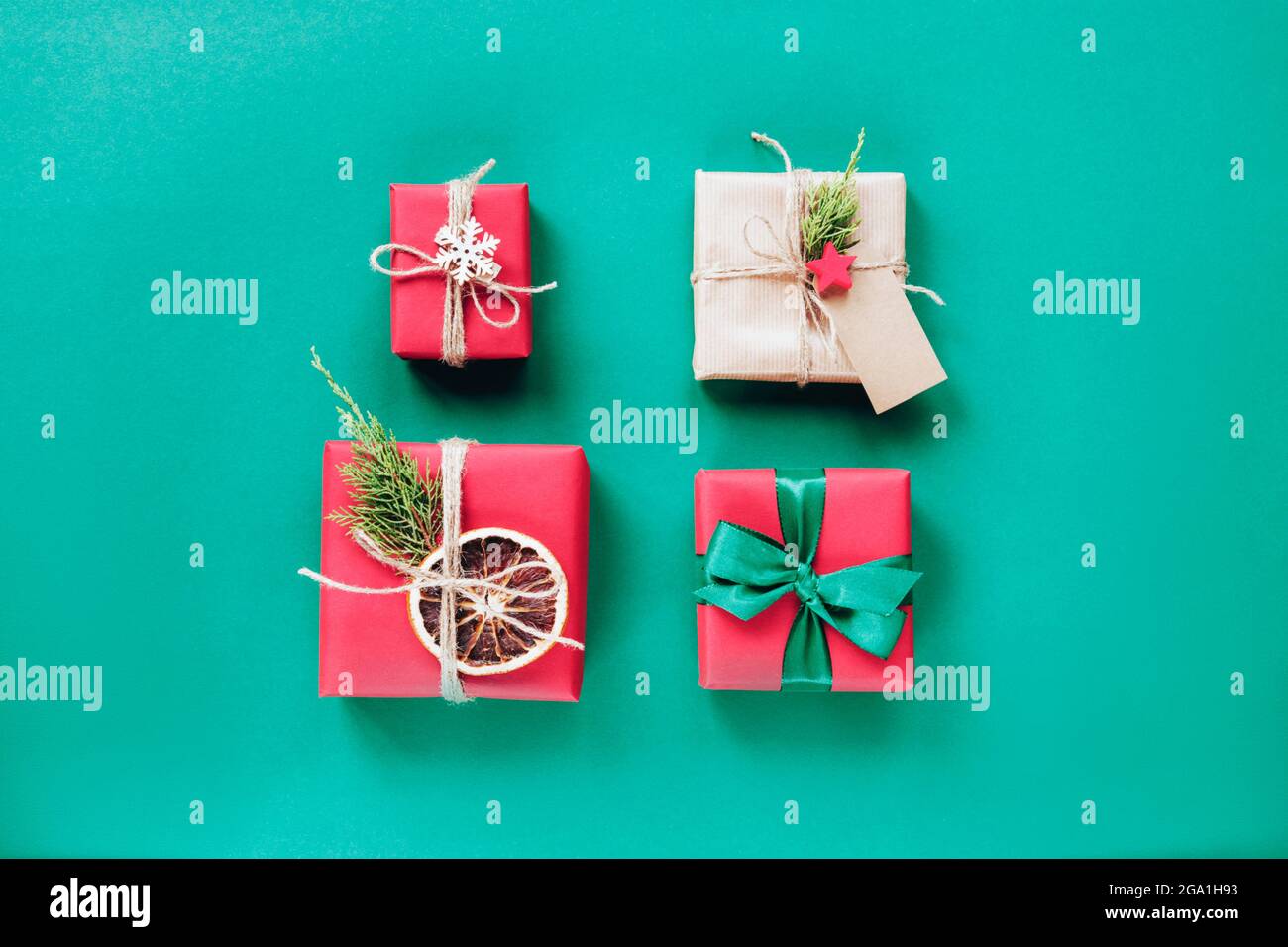 Rangées soignées de quatre boîtes-cadeaux de noël artisanales rouges sur fond vert. Vue de dessus, plan d'appartement. Concept de la nouvelle année. Banque D'Images