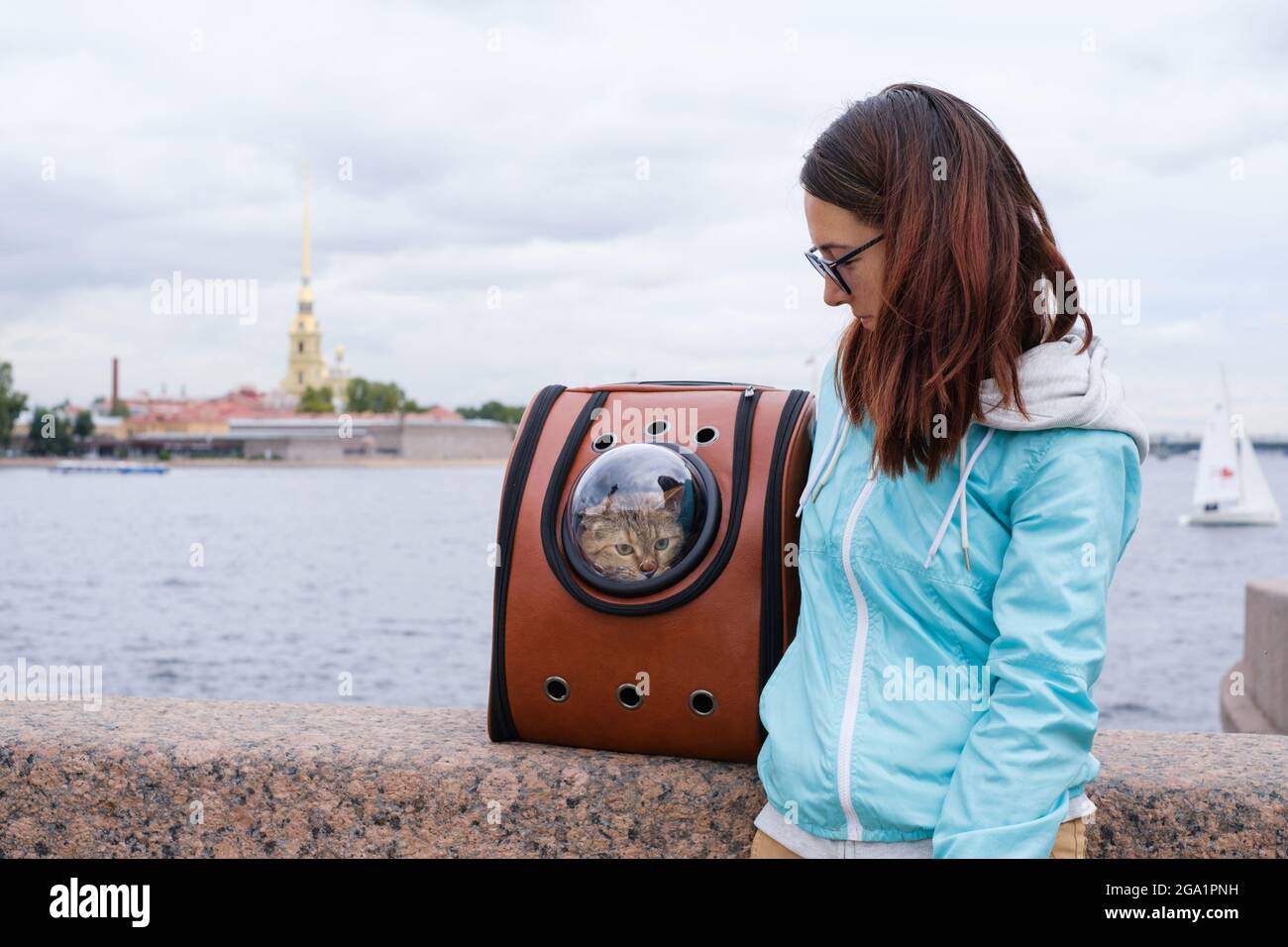 Chat de voyageur dans un sac à dos sur le remblai de Saint-Pétersbourg avec son propriétaire. Banque D'Images